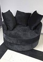 Front view of dark grey round chair with three matching pillows on tiled floor