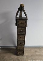 Front view of the hand carved wooden cabinet with primitive figure and six drawers.