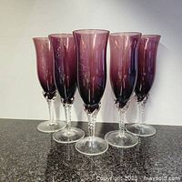 Front view of all five amethyst champagne glasses standing upright, showing twisted clear glass stems and rich purple bowls.