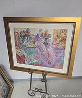 Framed print 'The Purple Shawl' by Mary Pavey displayed on an easel, showing front view with gold coloured frame and pastel colors in the print.