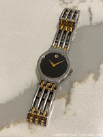 Photo of vintage Movado ladies' wristwatch showing integrated two-tone stainless steel and gold bracelet, and black Museum dial with single gold dot at 12 o'clock.