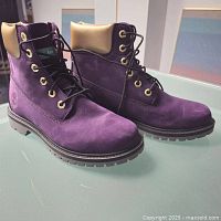Pair of purple suede Timberland ankle boots with gold leather padded collar, black laces, and lug soles.