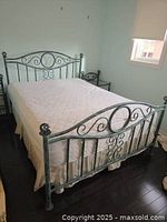 Full view of queen size wrought iron bed frame with mattress and box spring, showing verdigris finish and decorative scroll details on headboard and footboard.