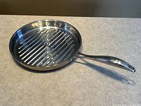 Full view of the stainless steel grilling pan showing ridged grilling surface and handle.