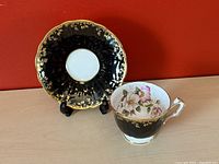 Tea cup and saucer set against red background showing front view of each item