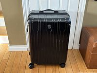 Front view of black Heys rolling luggage case showing the front panel, integrated handle, and four double spinner wheels.