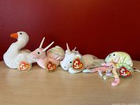 Four TY Beanie Babies plush toys on red background, showing original TY tags