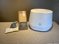 Composter unit with box of filter media sachets and starter packets laid out on countertop