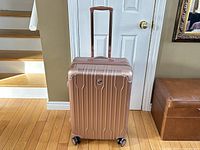 Front view of pink Heys hard shell rolling luggage case with telescoping handle extended and four wheels visible.