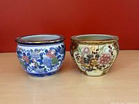 Two round Chinese ceramic planter pots side by side on a wooden surface with a red background