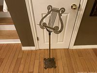 Full view of the vintage brass music stand showing the harp-shaped sheet music holder and tripod base.