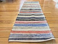 Full length view of the rag runner on hardwood floor showing multicolored horizontal stripes and texture.