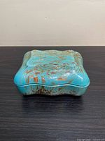 Front angled view of rectangular trinket box showing aquamarine color with bronze sparkle patterns on lid and sides.