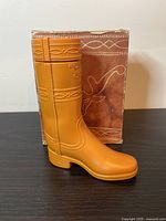 Side view of tan boot-shaped container with decorative western detailing.