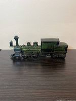 Side view of the dark green glass train-shaped bottle showing the locomotive and coal car details.