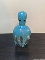 Front view of the hand blown glass octopus paperweight showing turquoise color with gold flecks and black eyes.