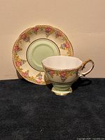 Photo showing the cup and saucer side by side on a dark surface with beige background