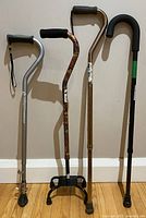 Group photo of four adjustable canes showing different styles and handle types against a wall.