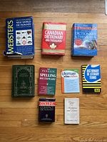 Top-down photo of nine books laid out on wood floor covering multiple dictionary and writing aid titles.