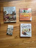 All four books arranged on wooden floor: large book on houseplants, medium 'Crops in Pots', medium 'Gardening Secrets', and a small book on succulents.