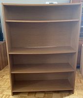 Front view of the bookshelf showing four shelves with two adjustable and overall maple veneer finish.