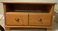 Front view showing two drawers with metal cup handles and an open shelf above