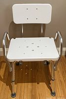 Front view of the white seat and backrest shower chair with metal frame and rubber tips on legs.