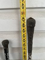 Photo showing length of one teen-sized hockey stick with black tape on the handle near the top, measuring around 48 inches