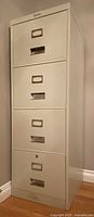 Light grey metal filing cabinet with four drawers showing front and side.
