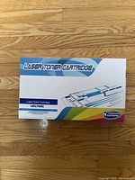 Boxed laser toner cartridge with text 'Laser Toner Cartridge' and model LSCLT406C on white blue multicolor packaging on wood floor.