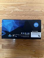 Box of sealed black premium laser toner cartridge SA-CLT-K406S with blue and black geometric design and printer icon.