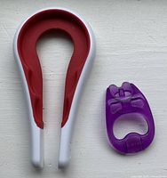 Pair of kitchen openers on white background: purple dual-use can and pop-tab opener, white and red multi-size bottle and jar opener.