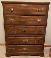 Front view of the five-drawer wooden chest showing brass-style handles and minor surface scratches.