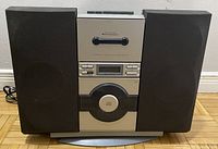 Front view of the retro stereo system with speakers attached, showing the closed cassette compartment and control buttons.