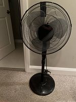 Full front view of the black Terra Gear oscillating pedestal fan showing the circular grill, black blades, and pedestal base.