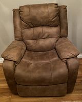 Front view of the brown faux leather recliner chair showing cushioned seat, high backrest, and padded armrests.