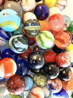 Close-up view of assorted vintage marbles showing diverse colors and types including solids, swirls, spotted, and cat's eyes.