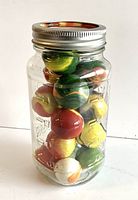 Glass jar containing 15 large vintage glass marbles in various colors and swirl patterns.