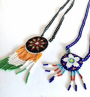Both vintage beaded necklaces with their full medallions and neck chains laid flat, showing bead colors and fringe dangles.