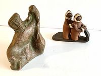 Two vintage Indigenous sculptures shown side by side, including the Inuit children on sled sculpture and the molded clay figurine.