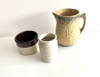 Set of three vintage stoneware pieces on white background showing pitcher, crock, and jar