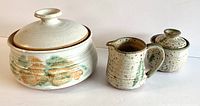 Set of three artisanal pottery items: casserole, creamer, and covered sugar pot arranged in a row
