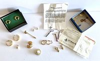 Full lot of costume jewelry items including earrings, studs, loose cubic zirconia, and informational flyer about niobium and titanium metals.