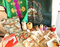 Display of entire lot including embroidered panels, tapestry purse, yarn, floss, silky fabric and Canadian flag
