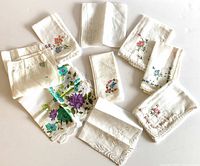 Overview of nine vintage ladies handkerchiefs showing various embroidery designs and crochet borders, some with printed patterns.