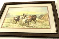 Front view of framed watercolour painting showing horses and rider in a natural landscape, including visible minor scuff marks on frame.