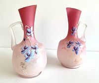 Pair of pink satin glass vases showing full front view with floral enamel decoration and frosted handles.