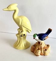 Pair of vintage ceramic flower frogs on white background, blue bird and yellow heron figurines
