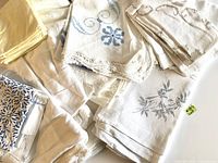 All vintage table linens arranged together showing embroidery and crochet details plus yellow napkins folded