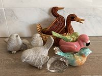 Full view showing all items together: 2 wicker duck baskets, 3 concrete bird figurines, 3 ceramic birds, one glass butterfly